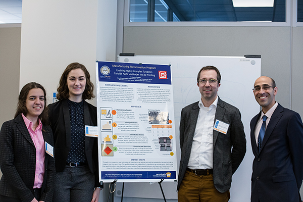 Four people standing with a poster.