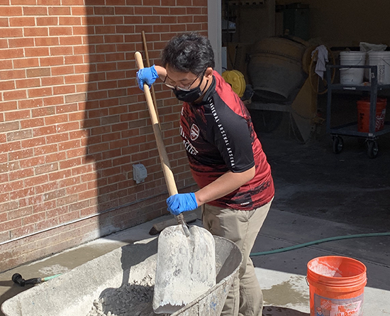 Student shoveling rocks in a wheelbarrel