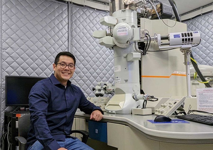 Researcher next to large machine in lab