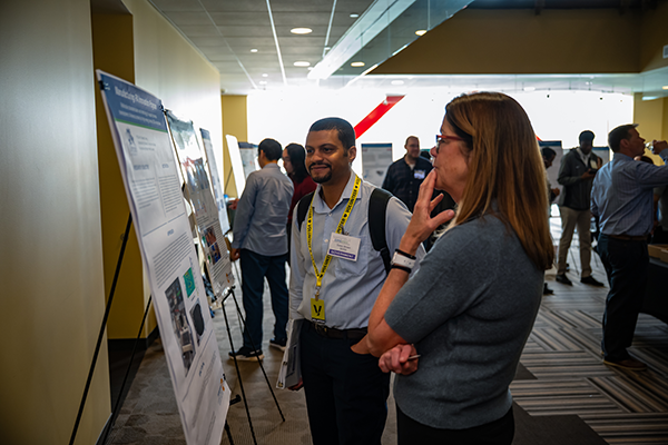 A man and a woman looking at a student's poster at the expo