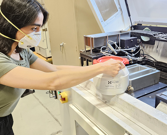 Female student in lab opening the lid of a container