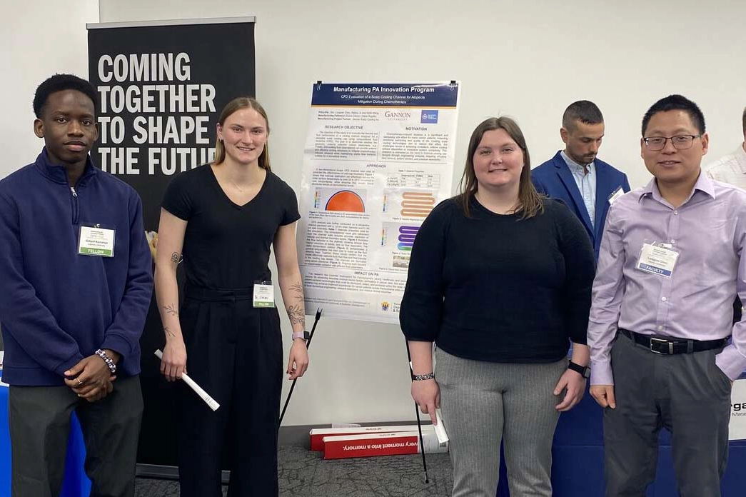 A group of four students with their poster during a poster session