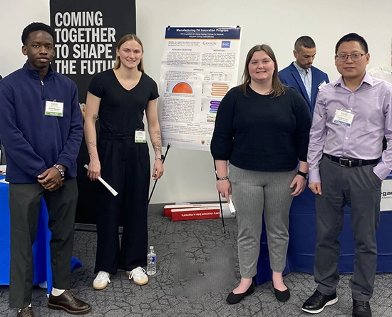 A group of four students with their poster during a poster session