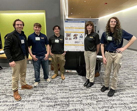 A team of five students in front of their poster